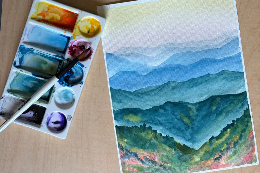 Watercolor painting of the Blue Ridge Mountains with palette and paintbrush