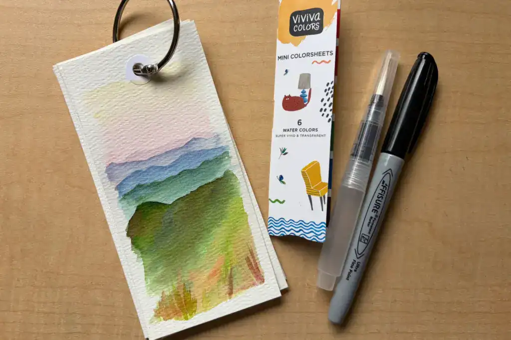 Handmade binder clip sketchbook with sample watercolors, water brush, and waterproof pen